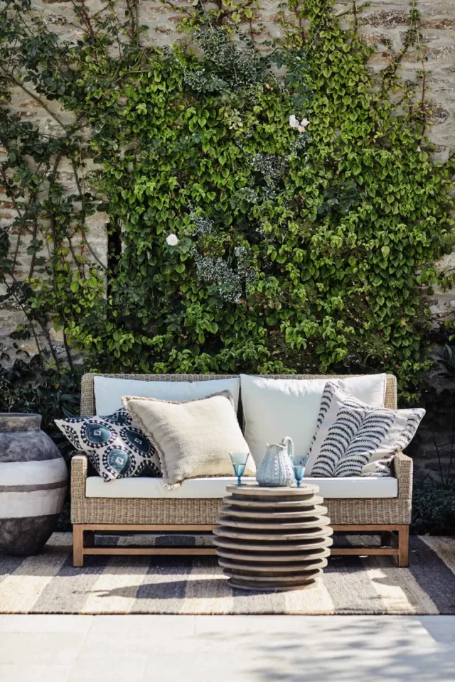 divano in rattan con cuscini e tappeto nel patio di OKA UK