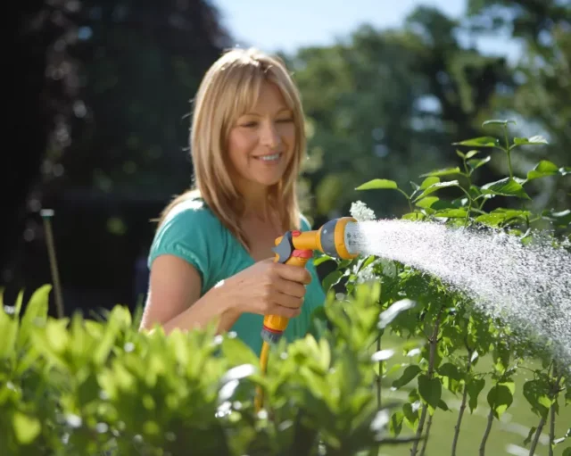 donna che innaffia il giardino con un tubo per innaffiare