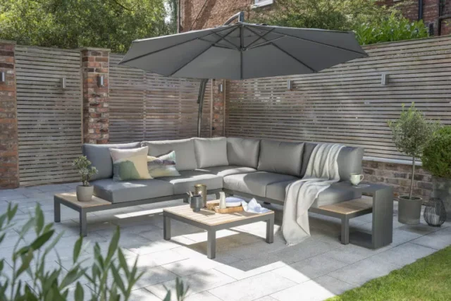 Grande divano ad angolo con un ombrellone a sbalzo su uno spazio patio