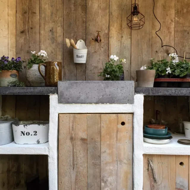 idee lavello esterno: lavandino in pietra tra vasi e fiori