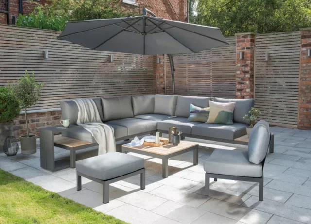 idee mobili da giardino: Elba divano basso ad angolo sul patio con poggiapiedi e ombrellone
