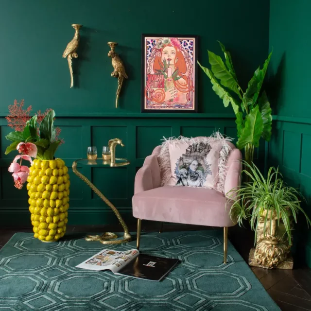 idee per piante da interno: piante in vaso funky nella stanza verde con poltrona rosa di AUDENZA