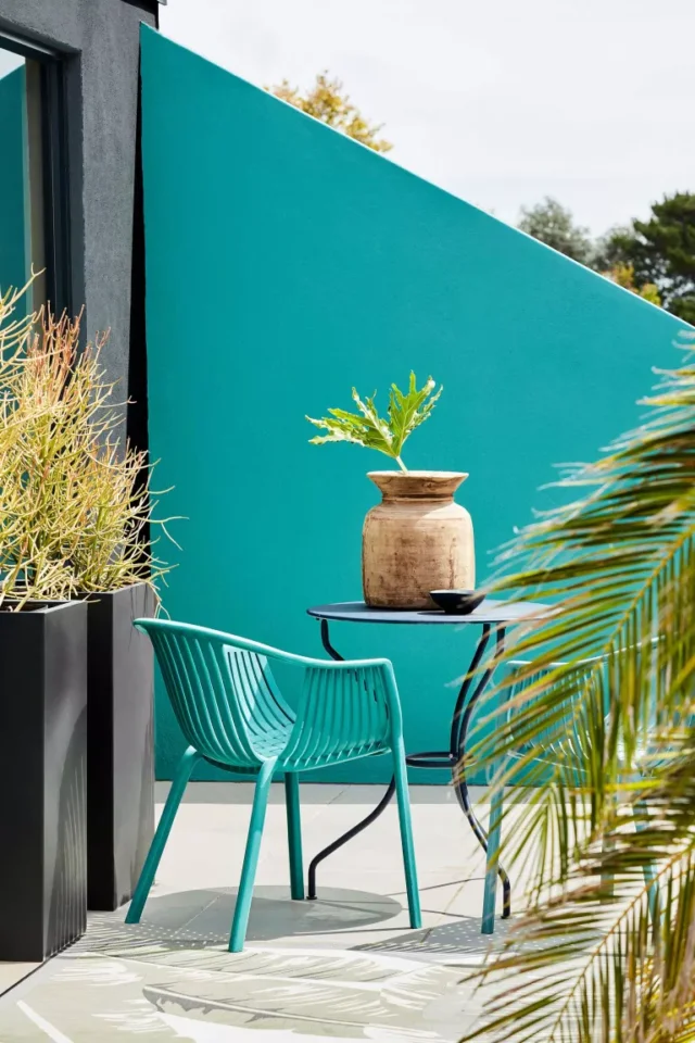 muretto dipinto di verde e sedia su piccolo patio